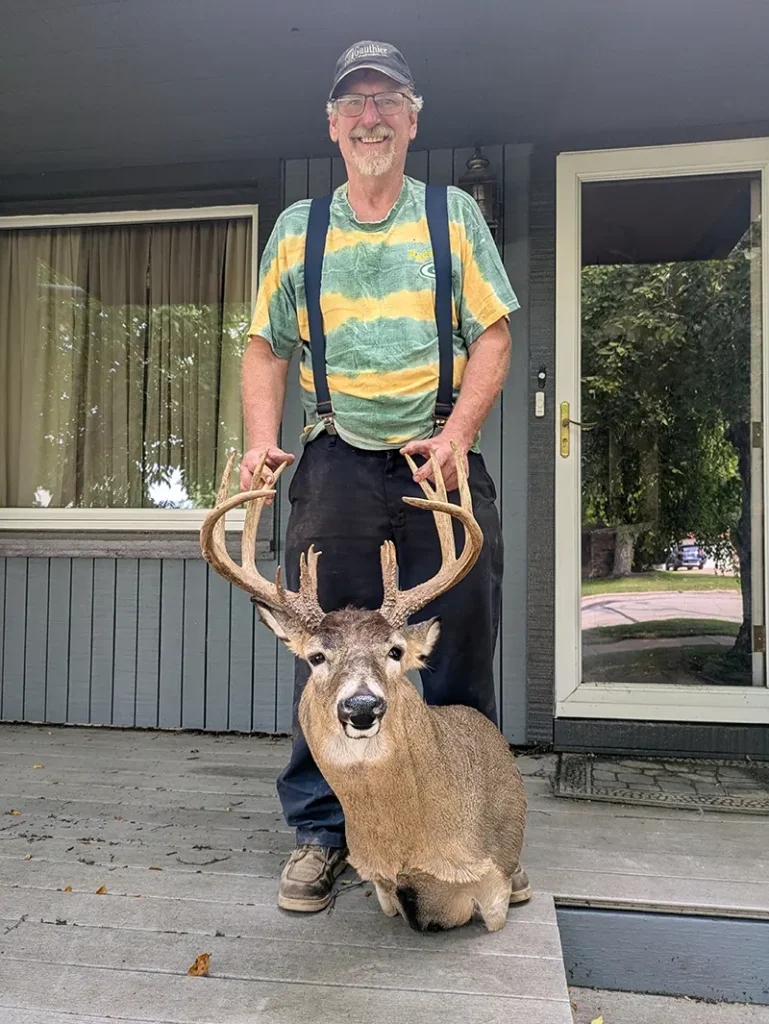 deer head held by man in stripped shirt