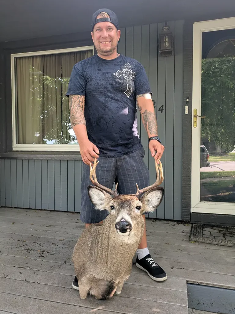 smiling man holding deer head