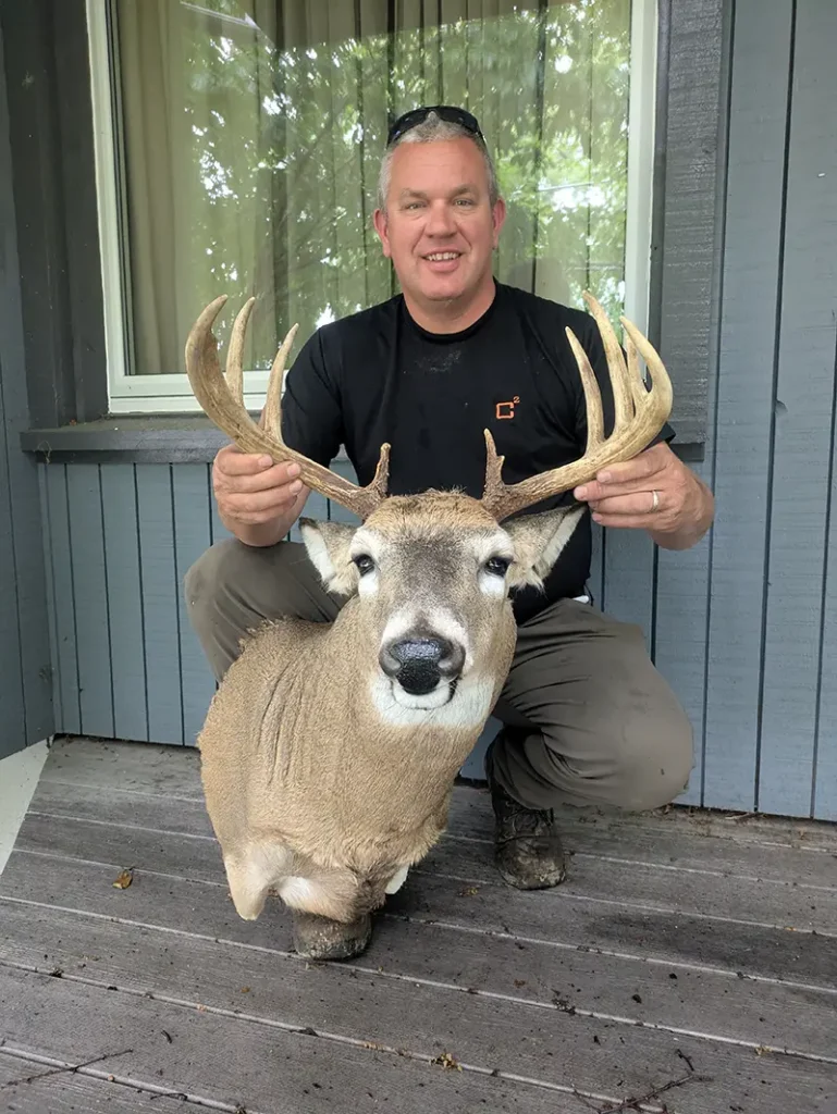 man on one knee holding deer head