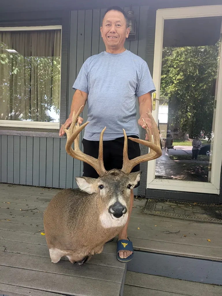 man holding large deer antlers on deer head